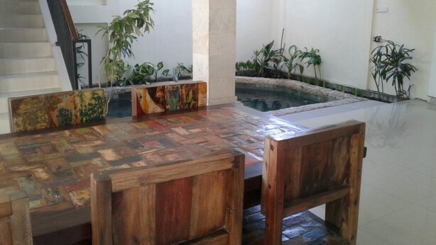 A dining area with a wooden table and chairs, a staircase, and potted plants. - Kunigen Villa Kuta Bali (Kerobokan)