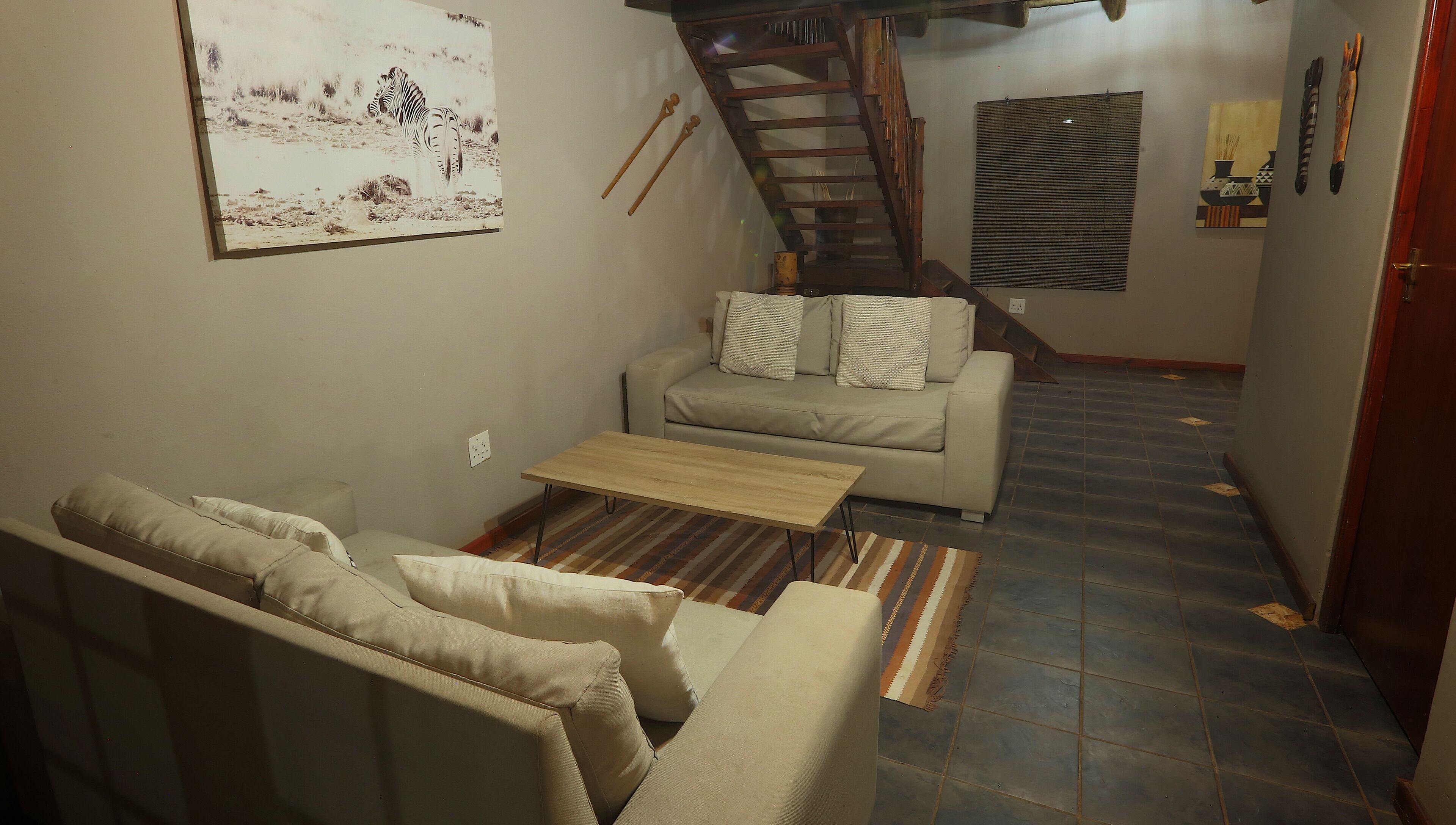 A living room with a sofa, a coffee table, and a staircase.