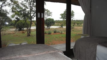 Enjoy breathtaking views of the surrounding landscape from this serene room featuring a comfortable bed, a wooden table, and a chair.