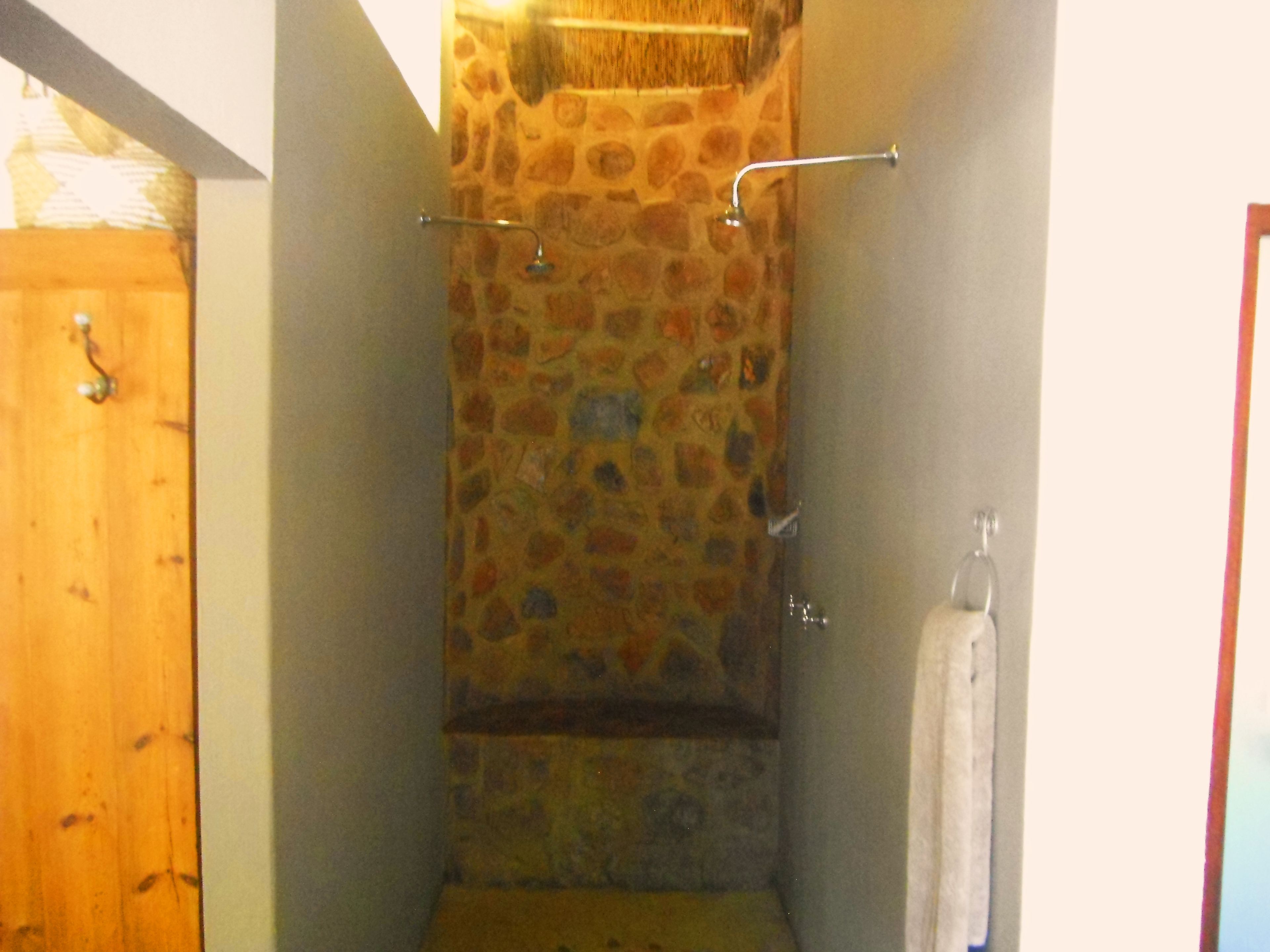 A bathroom with a stone wall, a shower, and a wooden door.