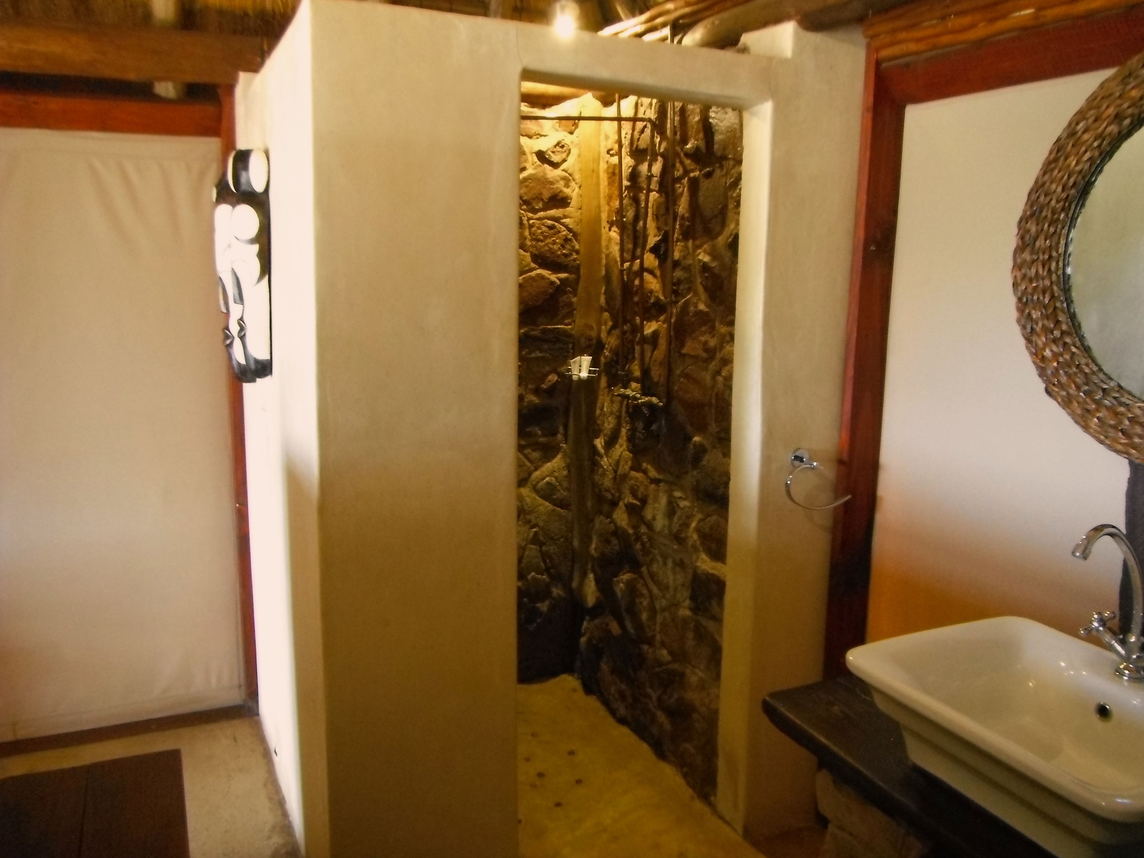 A bathroom with a stone wall, a sink, and a mirror.