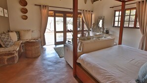 Een kamer met een bed, een slaapbank, een eettafel en een raam met gordijnen.