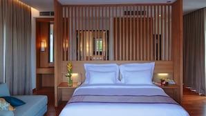 Ein modernes Hotelzimmer mit einem großen Bett, einem hölzernen Kopfteil und Blick durch eine Lamellenwand.