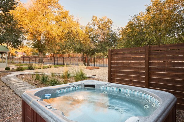 Relax in a serene hot tub surrounded by lush trees and a scenic walkway.