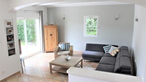 Un salon comprenant un canapé, une table basse, un fauteuil en osier et un meuble.