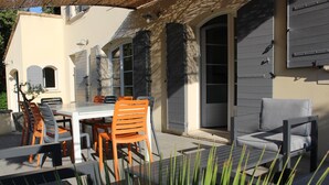 Une terrasse extérieure avec une table et des chaises, un canapé et une plante en pot.