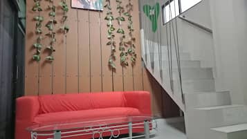 A red sofa, a glass table, and a staircase with a green heart decoration.