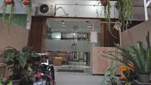 Een overdekte ingang met een motorfiets ervoor, plantenpotten en een houten hek.
