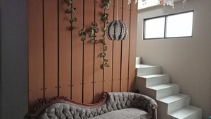 Een kamer met een wand van houten panelen, een bank en een trap.