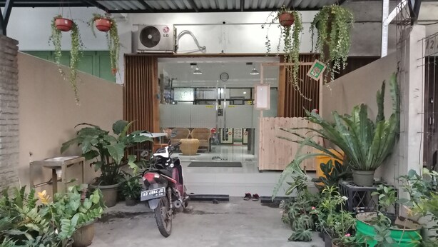 Een motorfiets geparkeerd in een overdekte ruimte met potplanten en een houten hek.