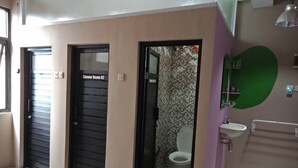 A bathroom with a tiled floor, a toilet, a sink, and a mirror. There are two doors labeled "Shower Room 02" and "Shower Room 01". - Bogor Cabin Inn - Hostel (Bogor)