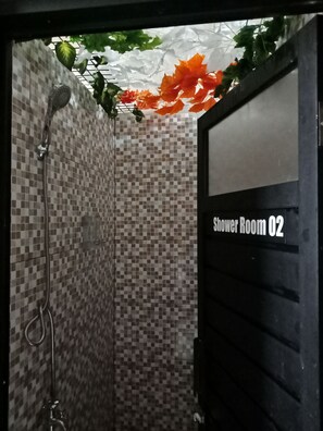 A shower room with checkered tile walls, a showerhead, and a door labeled "Shower Room 02". - Bogor Cabin Inn - Hostel (Bogor)