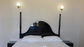 Un lit avec une literie blanche, deux lampes de chevet et une tête de lit sombre.