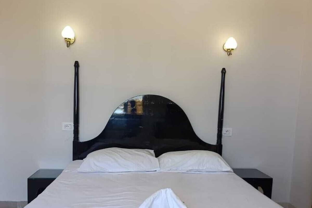 A bed with white bedding, two bedside lamps, and a dark headboard.