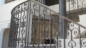 Un escalier à plusieurs niveaux, doté de rampes en métal noir ouvragé et d’un pilier central.