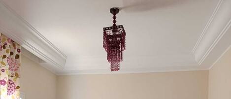 Une chambre avec deux lits, un lustre et une fenêtre avec des rideaux.