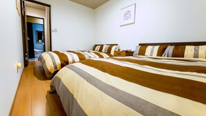 A hotel room with two beds, a wooden floor, a bedside table, and a wall-mounted picture. - 73BNB House in Chiyozaki (Osaka)