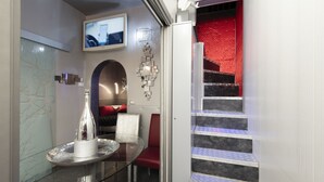 A modern hotel lobby with a glass table, red leather chairs, a TV, and a staircase with red accents. - Suite Sweet Rome (Rome)