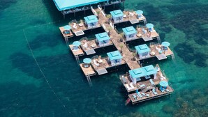 An aerial view of a floating hotel with multiple levels, clear blue water, and a beach area with umbrellas. - Granada Luxury Beach - All Inclusive (Alanya)