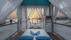 A private balcony with a view of the sunset over the water, a small table with a chair, and a minibar. - Granada Luxury Beach - All Inclusive (Alanya)