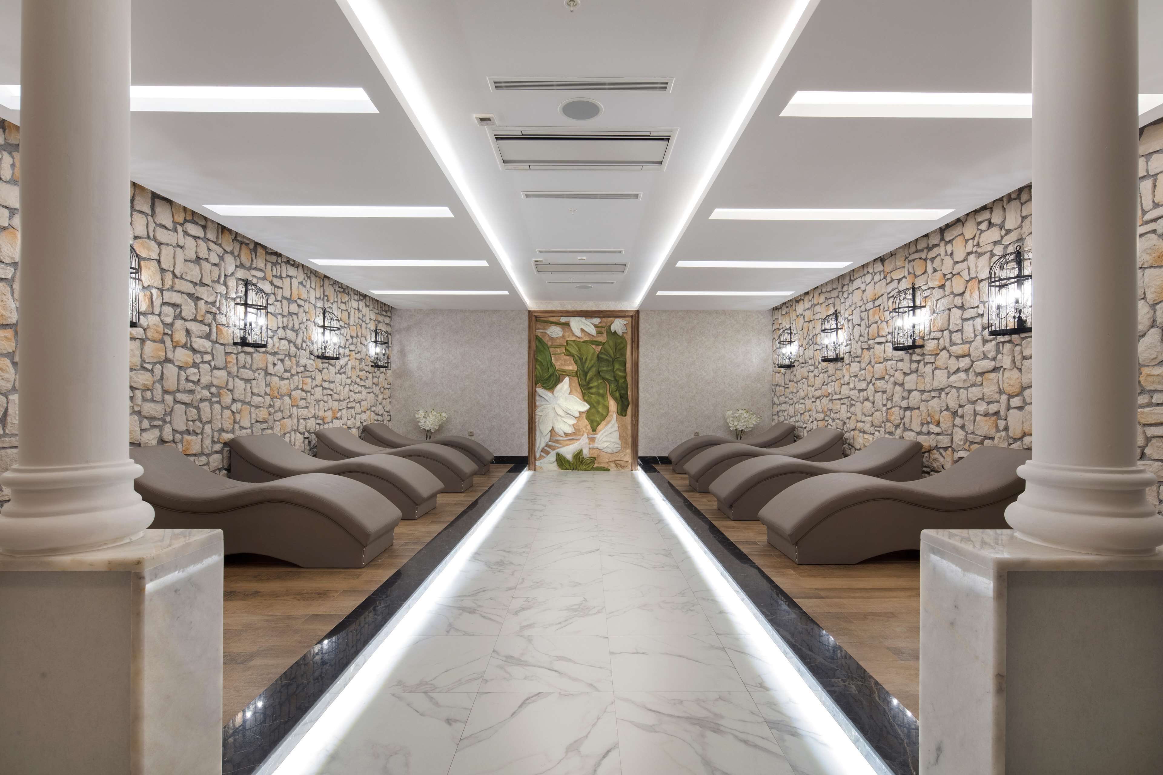 A spa room with a marble floor, stone walls, and multiple massage chairs.