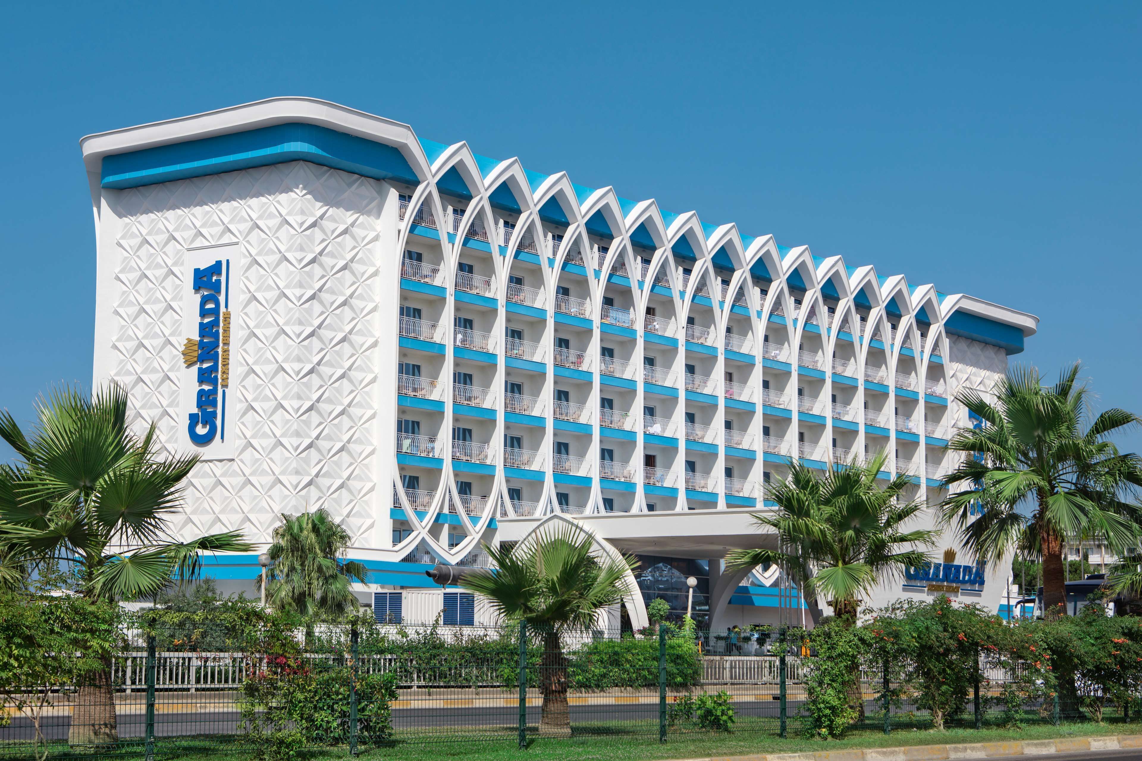 A large hotel with a distinctive white and blue facade, multiple balconies, and a central atrium.