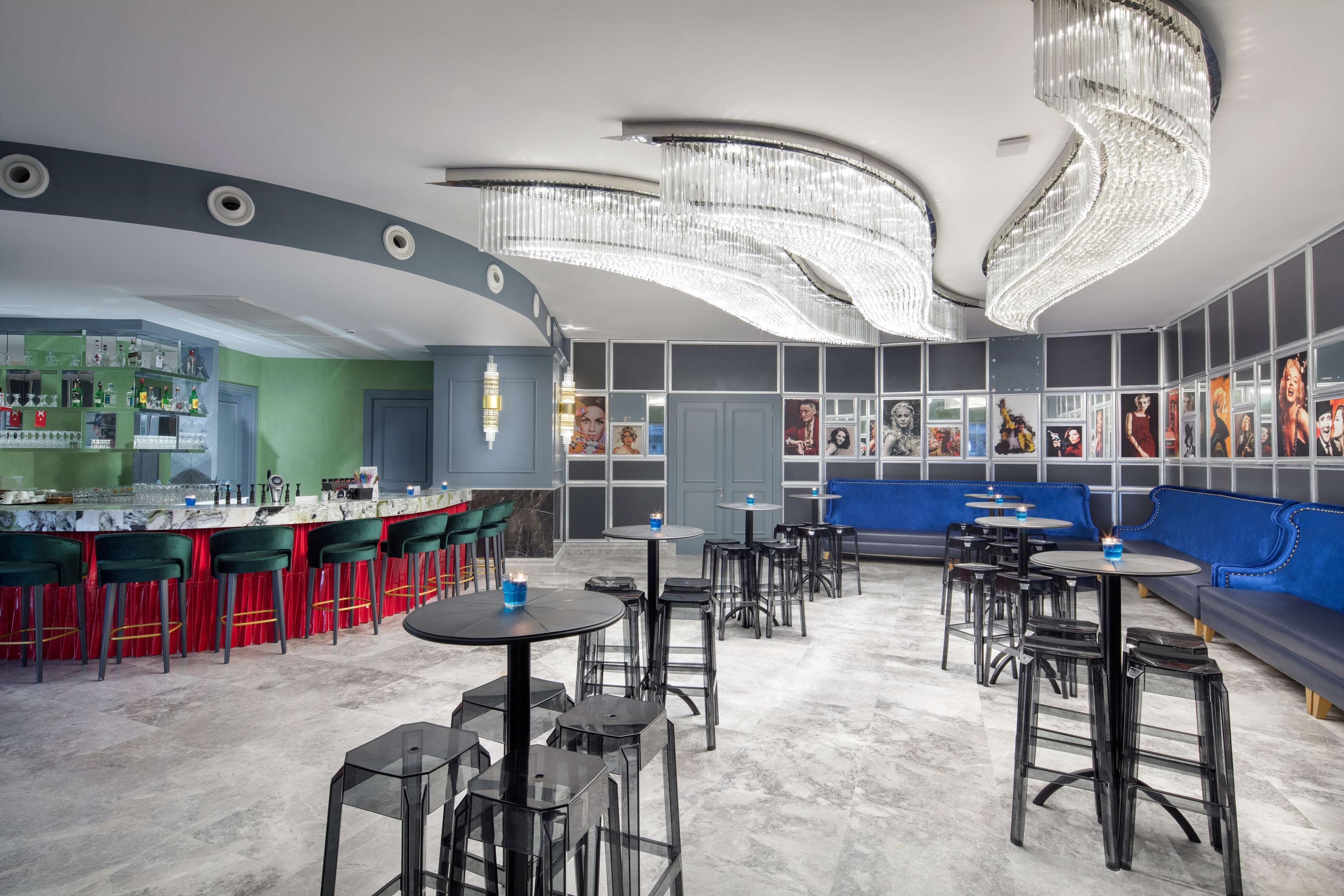 A modern bar area with a curved ceiling, bar stools, and a seating area with tables and chairs.