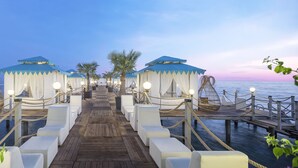 A wooden pier leading to a row of white canopied seating areas with rope barriers, overlooking a body of water. - Granada Luxury Beach - All Inclusive (Alanya)