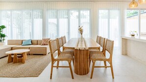 Una sala de estar moderna con una gran mesa de comedor, sillas de mimbre, un sofá y un ventilador de techo.