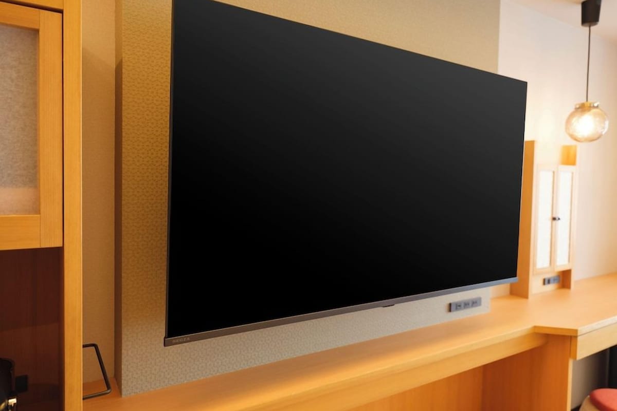 Un televisor de pantalla plana montado en una pared en una habitación con muebles de madera y una lámpara colgante.