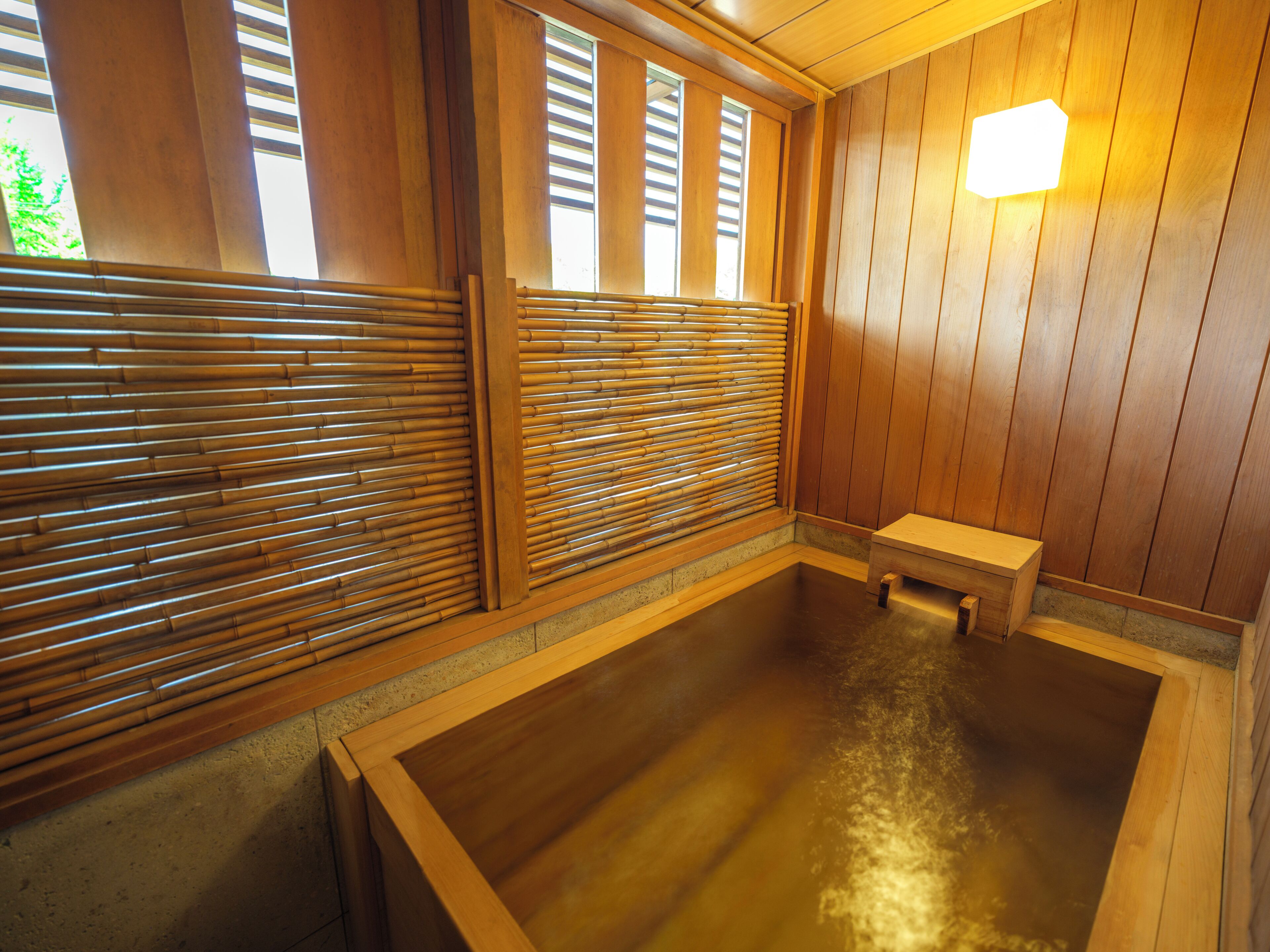 A traditional Japanese onsen with wooden sliding doors, a bench, and a tiled floor.