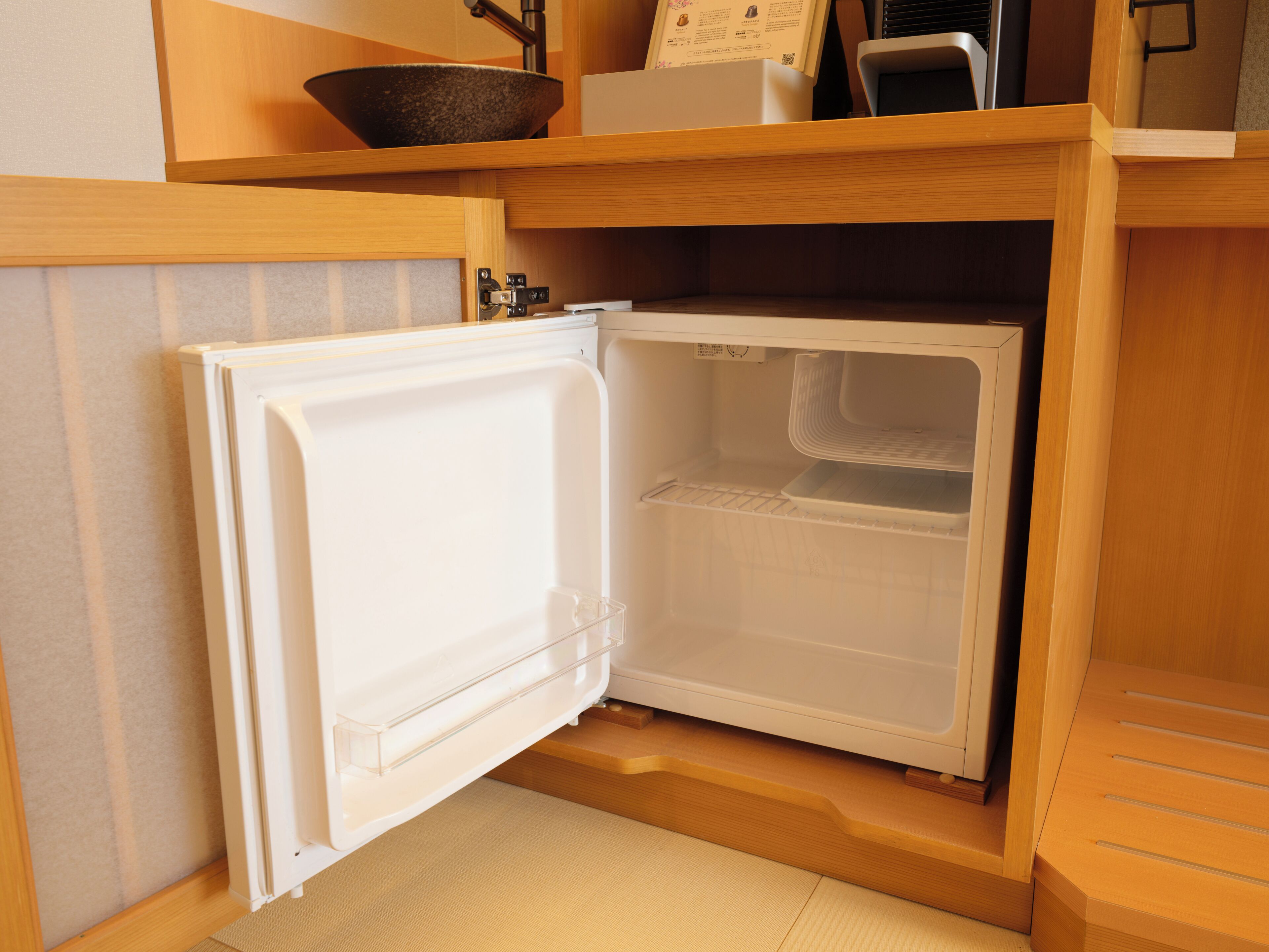 A compact refrigerator with a freezer compartment, a built-in shelf, and a control panel.