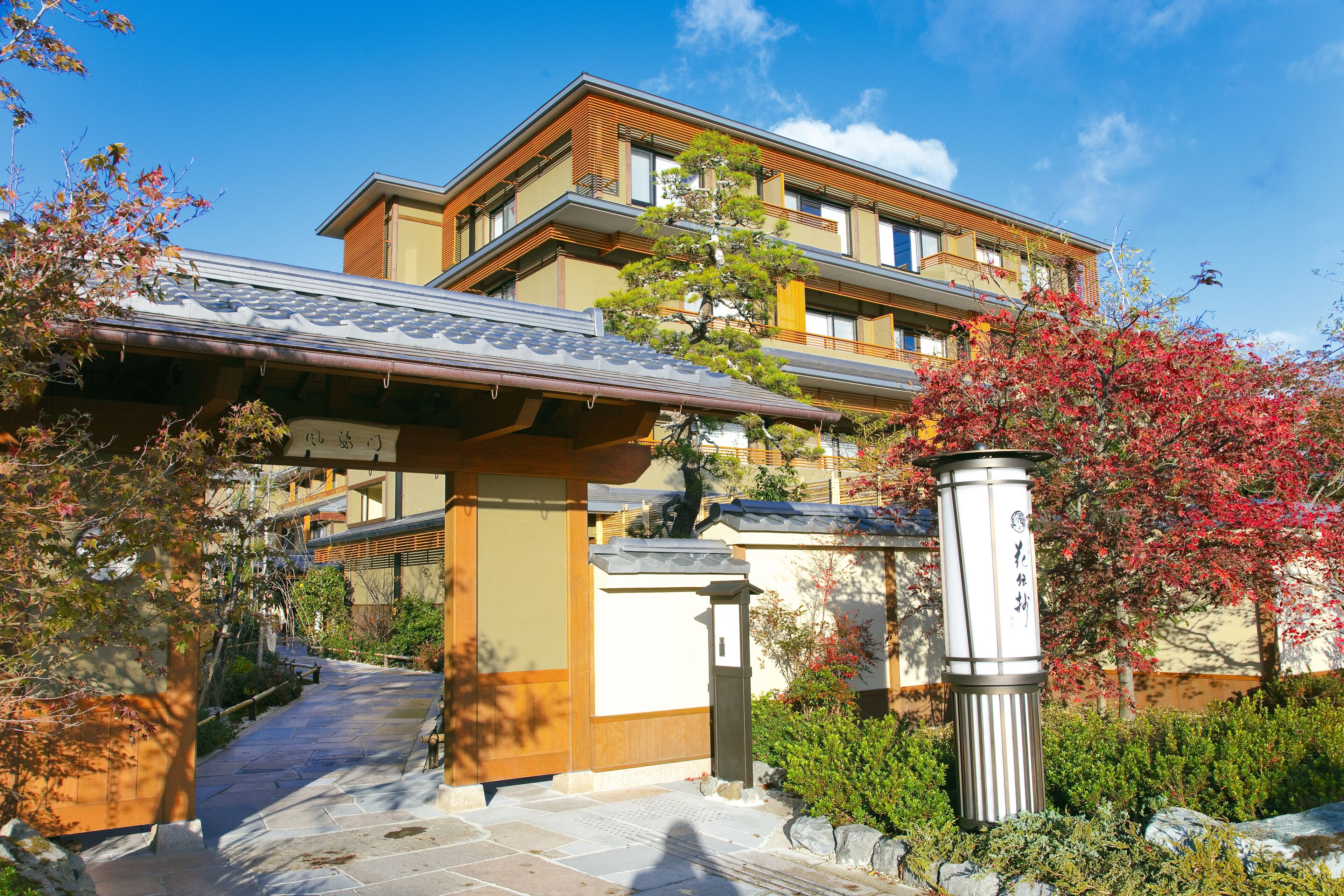 A traditional Japanese building with a tiled roof, wooden beams, and a stone pathway leading to the entrance.