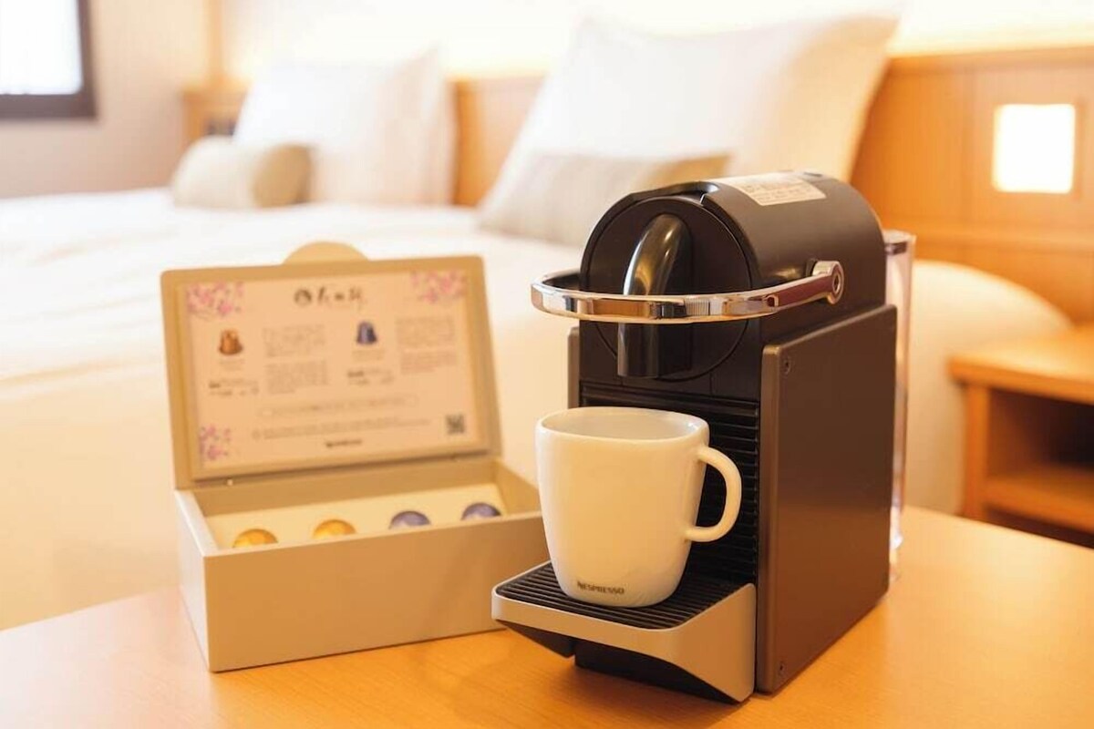 Una cafetera con una taza y un atril para el menú en una habitación de hotel.