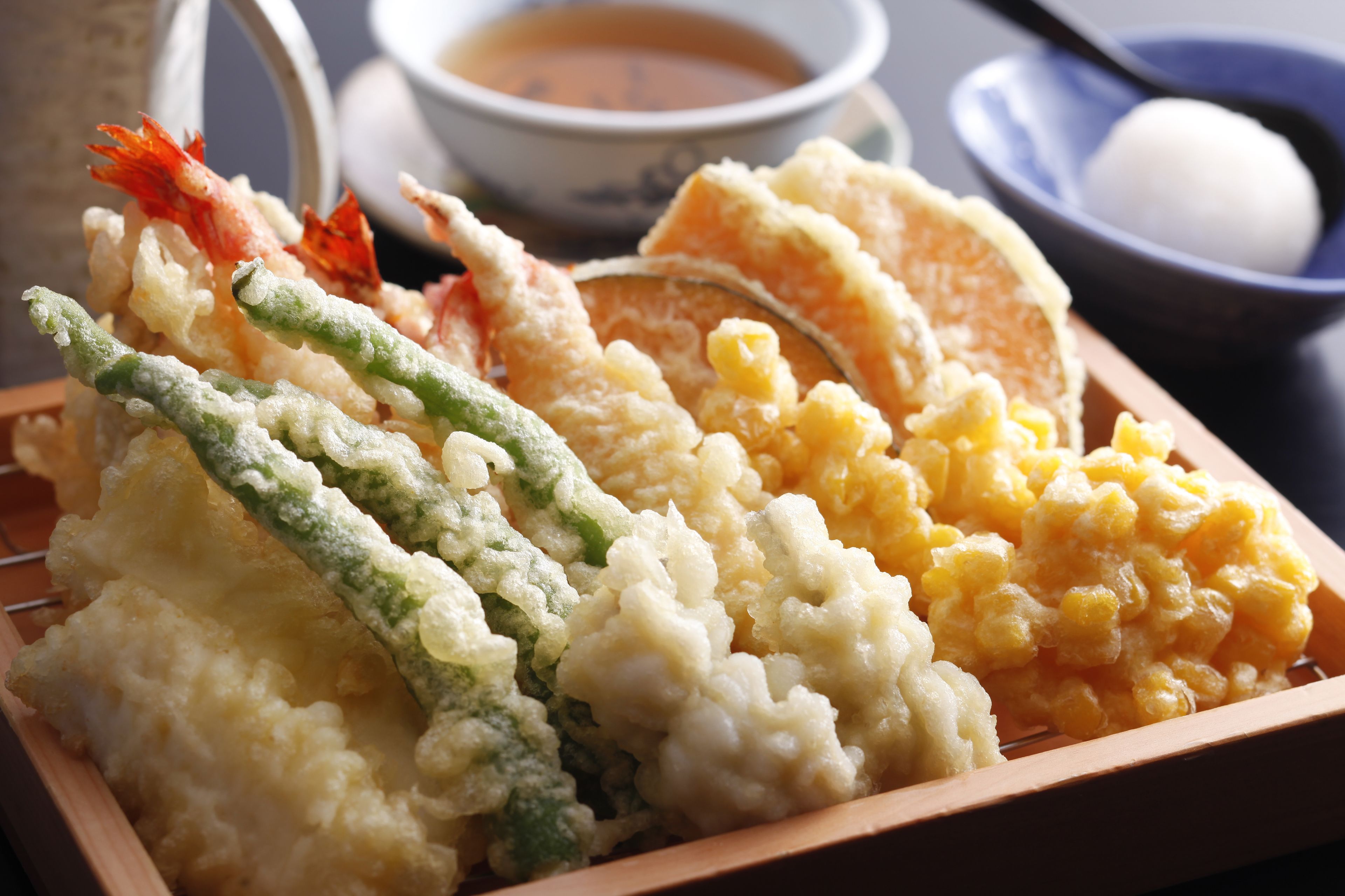 A tray of tempura with shrimp, green vegetables, and corn.