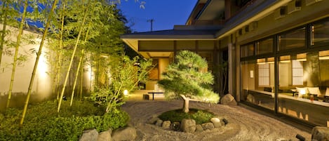 A well-maintained garden with rocks, a small tree, and bamboo plants.