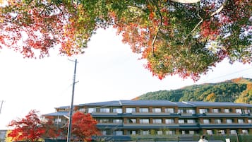 A multi-story building with a modern architectural style, surrounded by trees with autumn foliage.