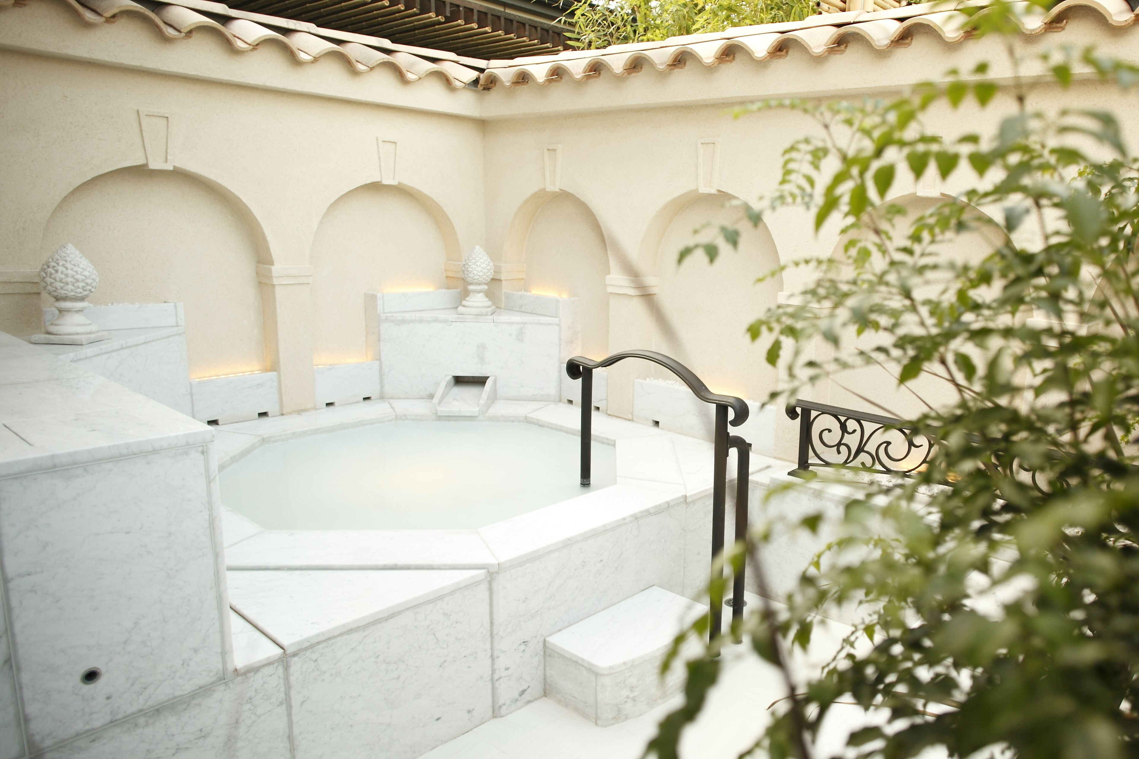 A spa area with a hot tub, marble steps, and decorative urns.