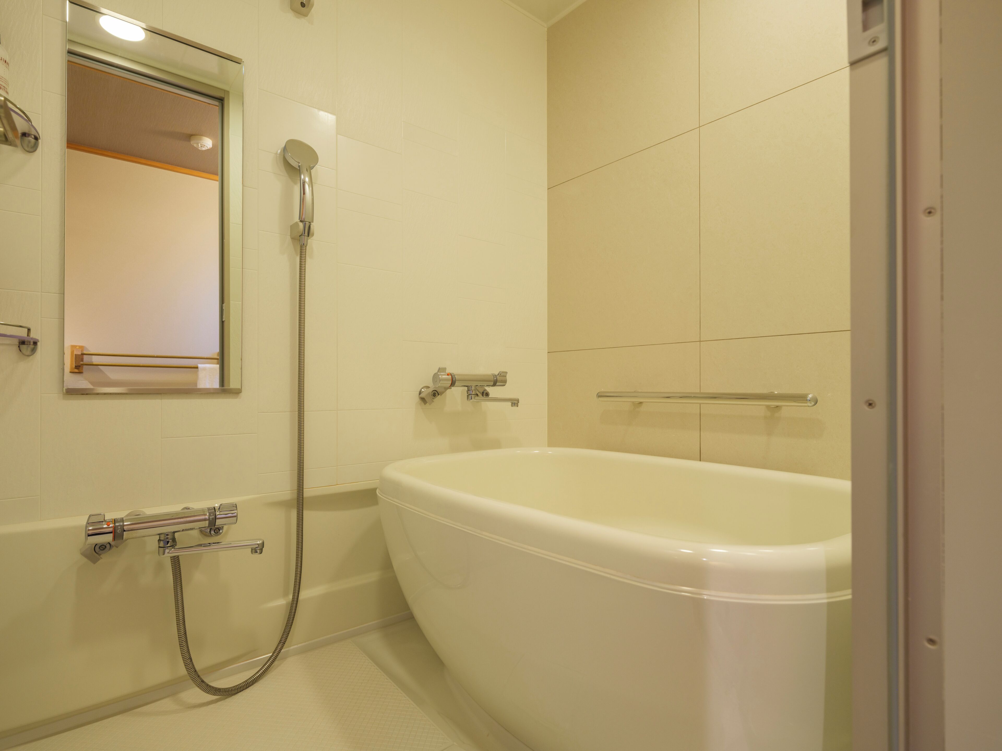 A bathroom with a bathtub, a shower, a mirror, and a towel rack.
