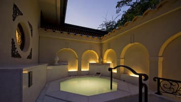 A spa area with a hot tub, arched alcoves, and a tiled floor.