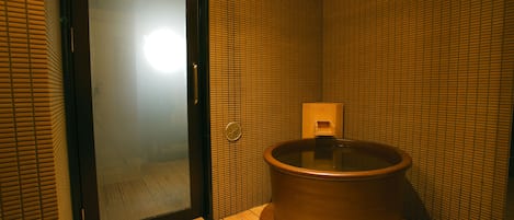 Une pièce dotée d’un plancher en bois, d’une grande baignoire en céramique et d’une porte-fenêtre coulissante.