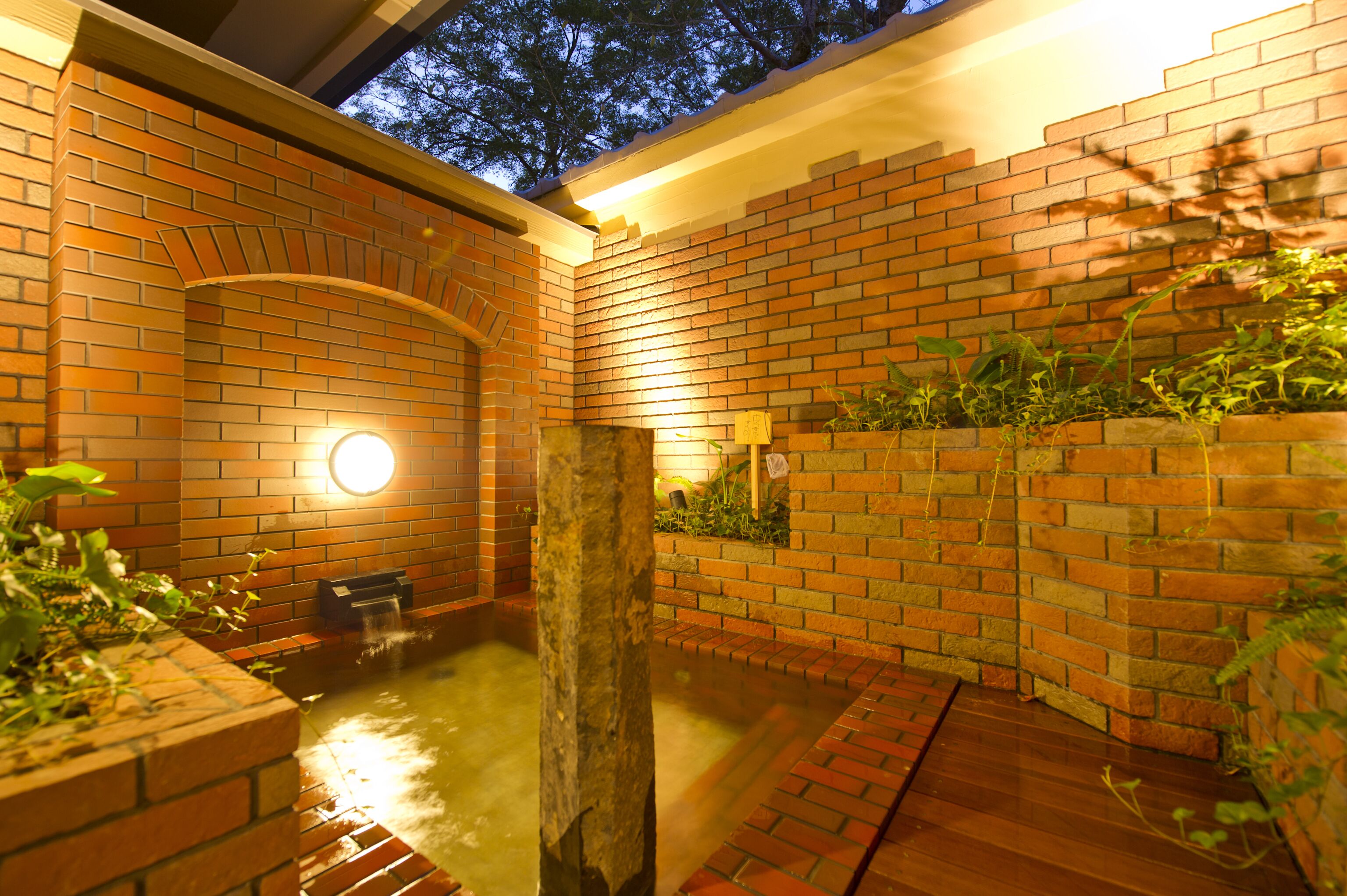 A brick-walled outdoor area with a water feature and a wooden post.