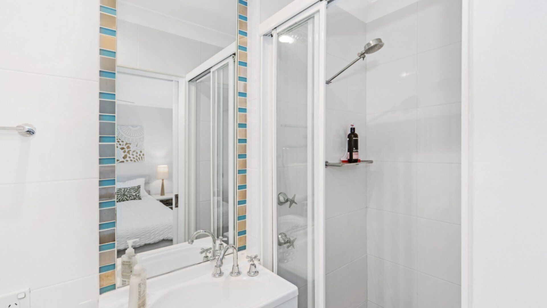 Une salle de bain moderne avec un lavabo blanc, un miroir et une douche.