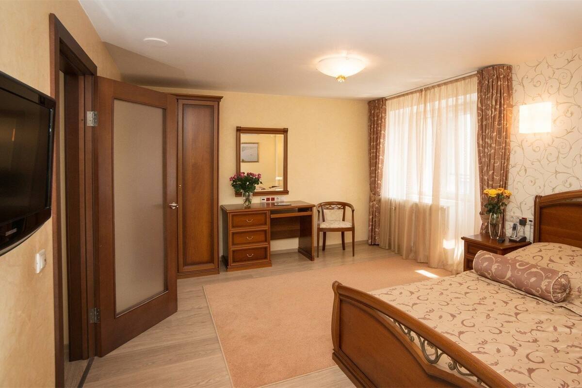 Hotellihuone, jossa on sänky, työpöytä, tuoli, televisio ja vaatekaappi.