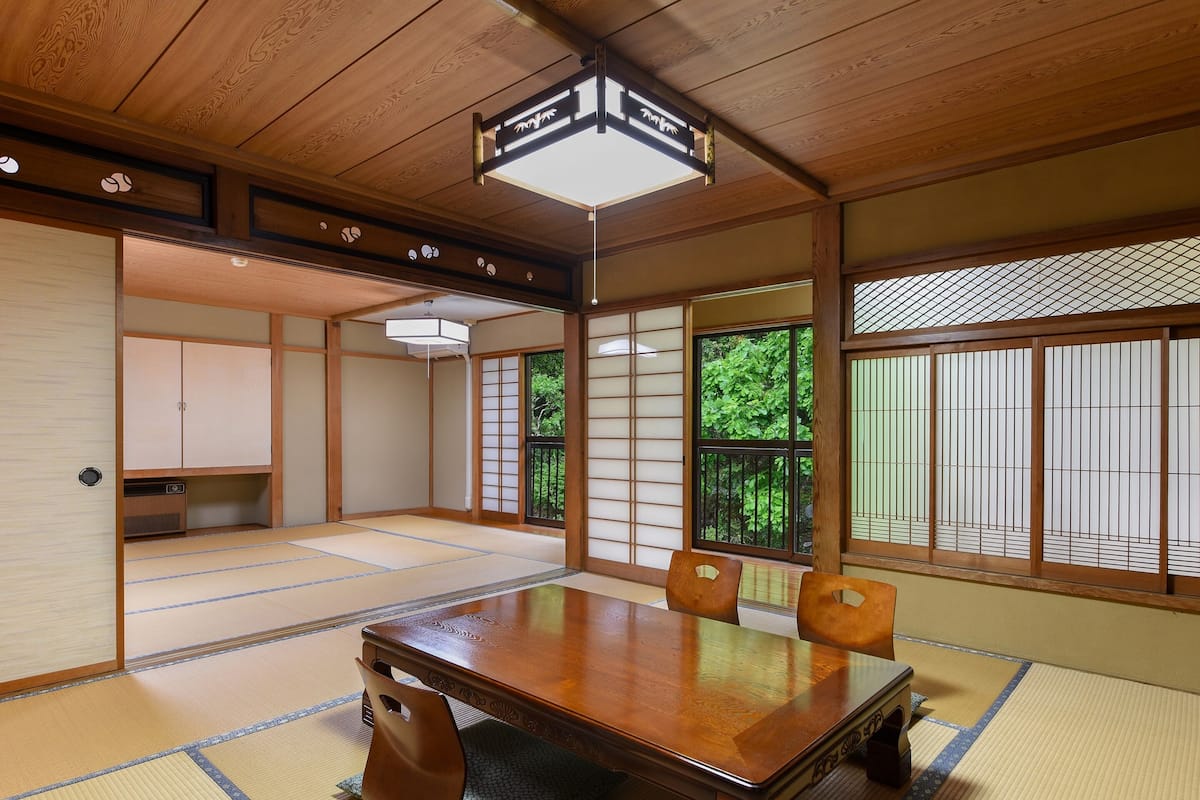 A traditional Japanese room with tatami flooring, a wooden table, and sliding doors.