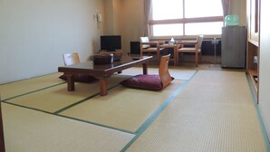 Perinteinen japanilainen huone, jossa on tatamimatto, matala pöytä tyynyineen, televisio ja jääkaappi.