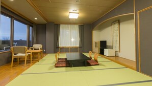 Perinteinen japanilainen huone, jossa on tatamimatto, matala pöytä ja puiset tuolit.