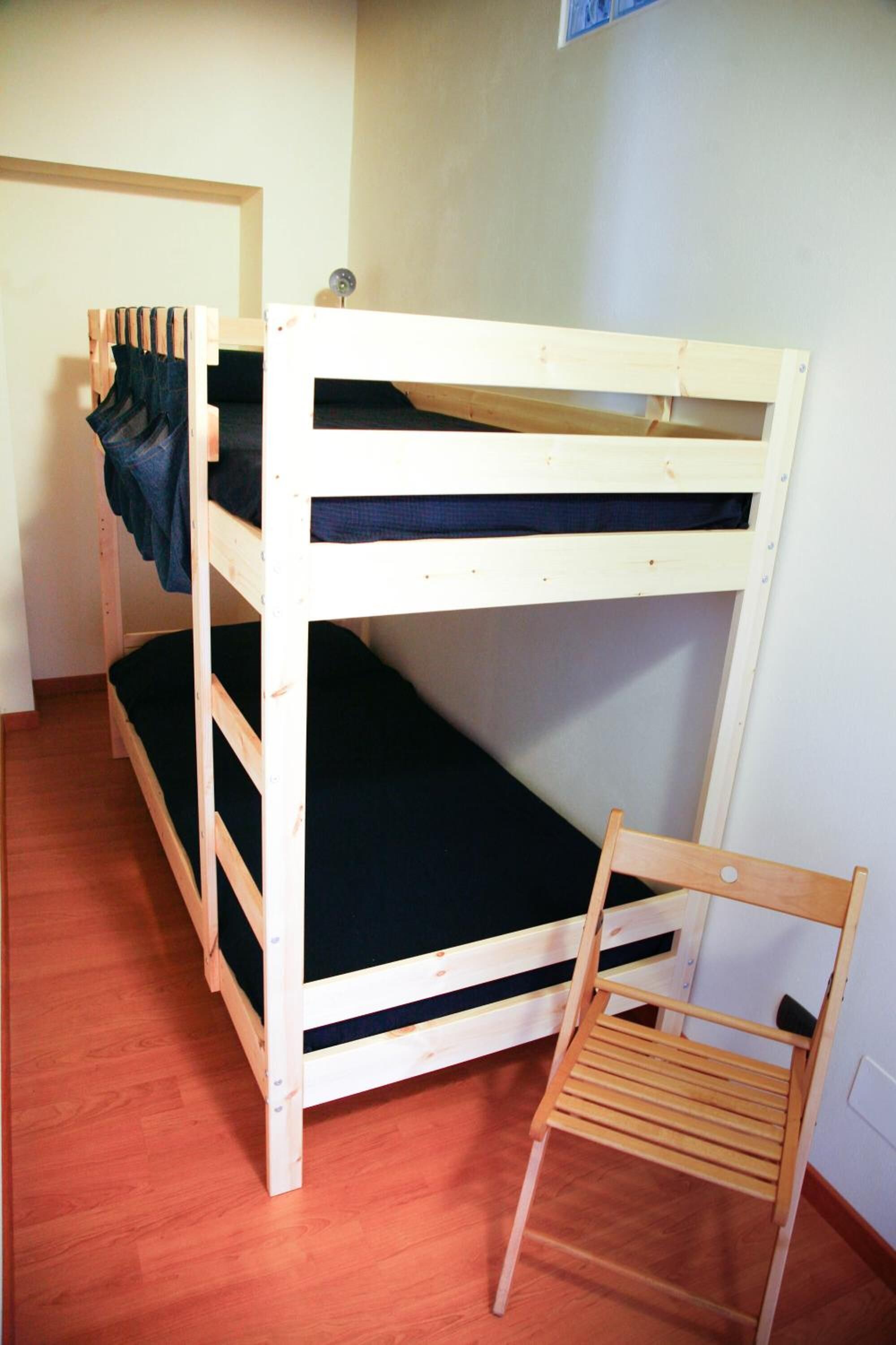 Una cama litera con una escalera de madera y una silla al lado.