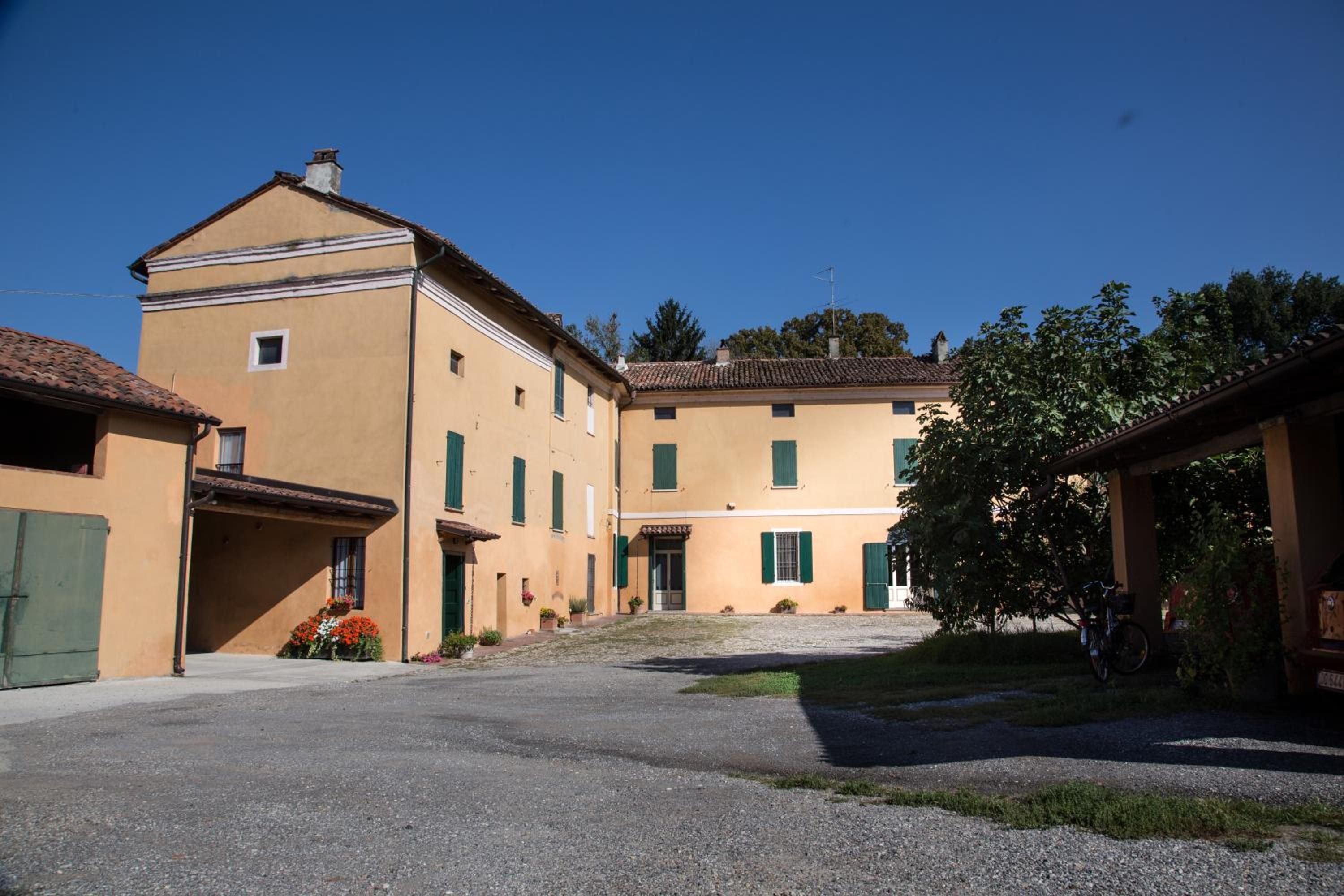 A courtyard with buildings, a gravel path, and a tree.