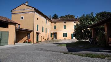 A courtyard with buildings, a gravel path, and a tree.